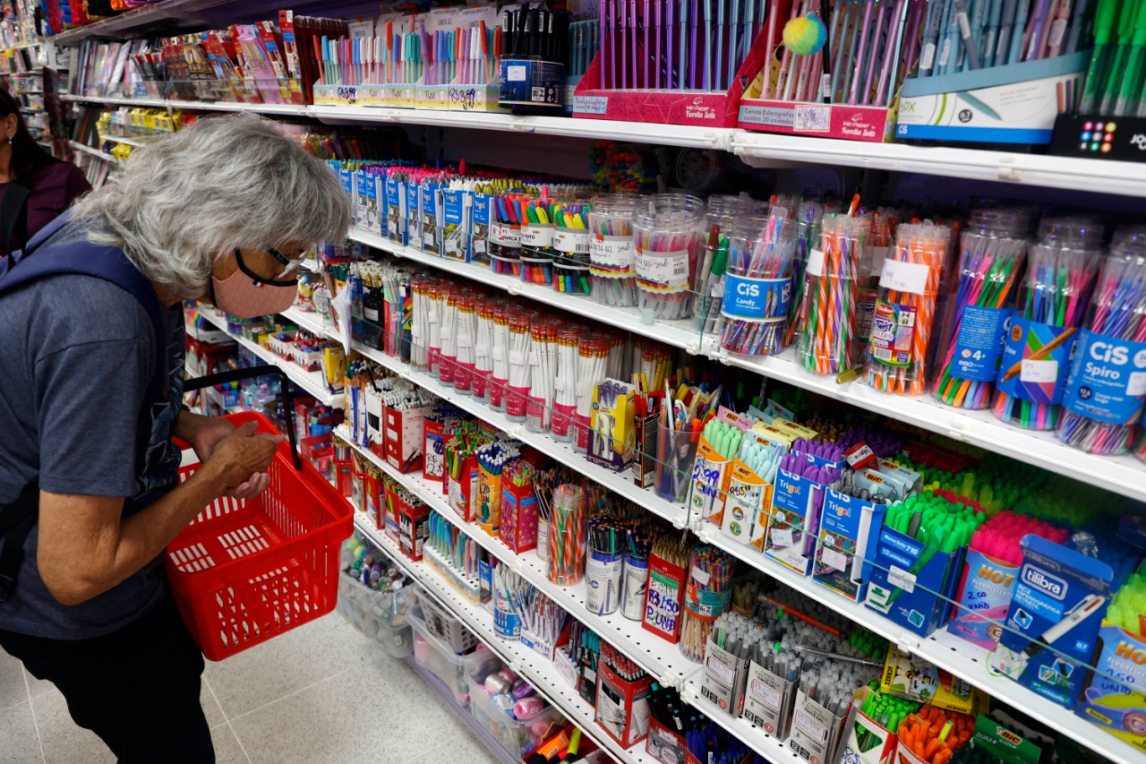 Imagem de cliente observando material escolar na prateleira.