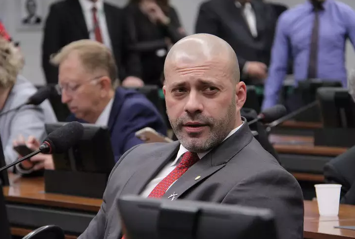 Imagem do ex-deputado Daniel Silveira sentado na sala de comissões.