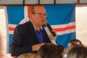 Imagem do secretário Jaime discursando com a bandeira de São Gonçalo como pano de fundo. 