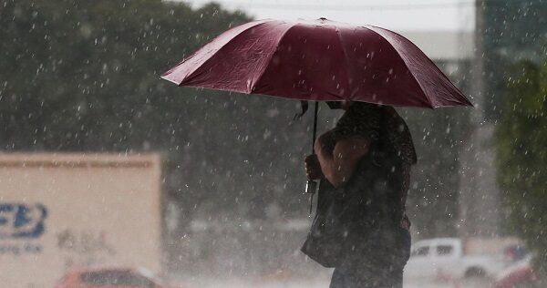 Imagem de senhora com sobrinha se protegendo da chuva.