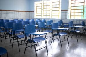 Imagem de sala de aula com cadeiras vazias.