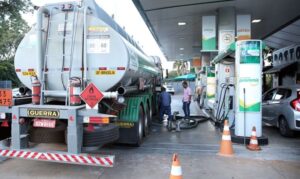 Caminhão tanque fazendo abastecimento em posto de combustível.