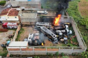 Imagem aérea de veículos incendiados em uma garagem.