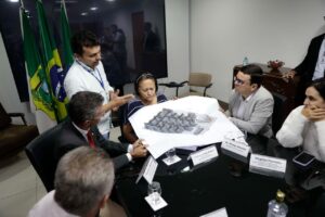 Governadora Fátima em reunião com equipe e observando uma planta de obras.