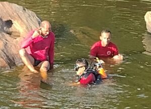 Bombeiros fazendo busca em rio para encontrar o corpo do jovem vítima de afogamento.